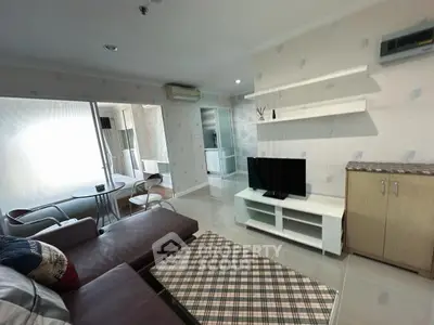 Modern living room with stylish furniture and TV, adjacent to a cozy bedroom, perfect for urban living.