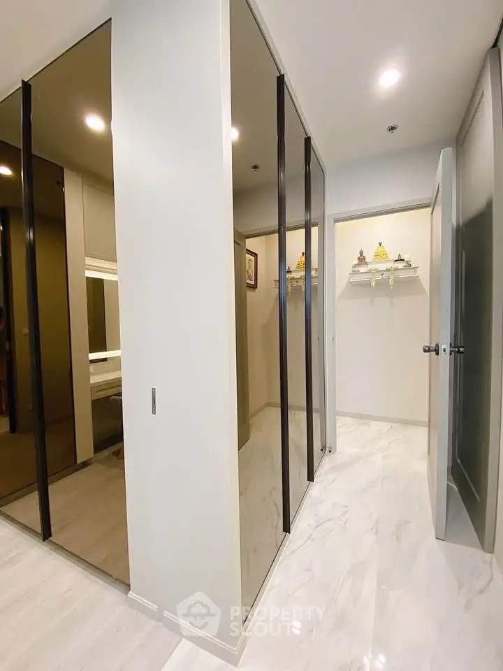 Modern hallway with sleek mirrored closets and marble flooring