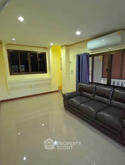 Spacious living room with leather sofa and air conditioning in modern home.