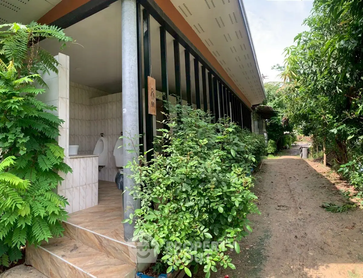 Charming outdoor restroom facility with lush greenery and tiled entrance.