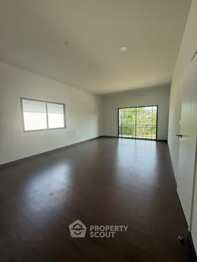 Spacious empty room with large windows and wooden flooring