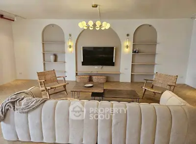 Elegant living room with modern decor, featuring a plush sofa, stylish chairs, and a wall-mounted TV.