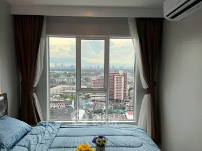 Spacious bedroom with stunning city view from large window, featuring modern decor and cozy bedding.