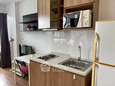 Modern compact kitchen with microwave and fridge in cozy apartment
