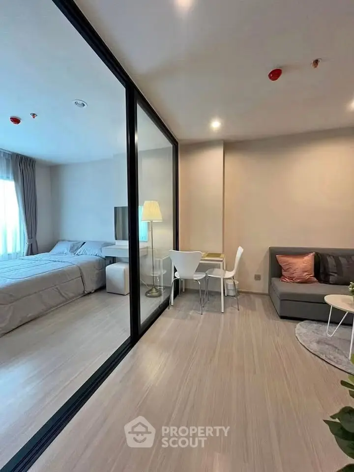 Modern studio apartment with glass partition, cozy living area, and elegant bedroom.