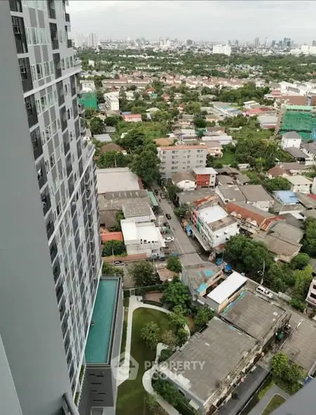 Stunning cityscape view from high-rise balcony overlooking urban landscape and greenery.