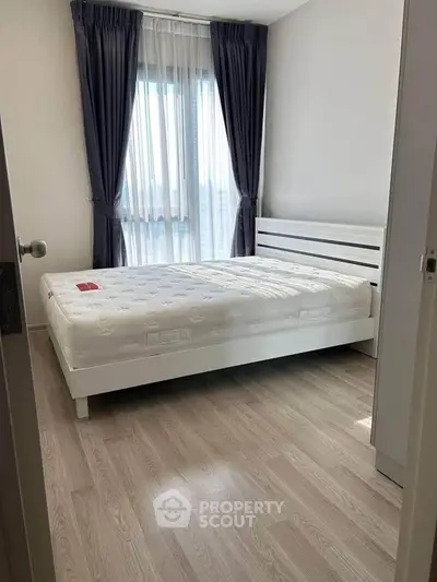 Modern bedroom with large window and elegant curtains, featuring a comfortable bed and sleek wooden flooring.