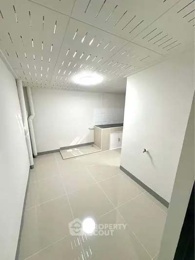 Spacious basement with sleek tiled flooring and modern ceiling design, ideal for storage or utility use.