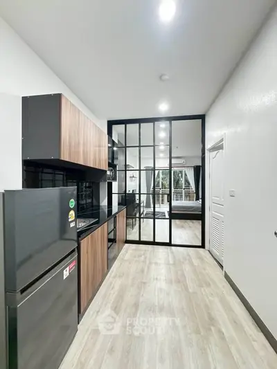 Modern kitchen with sleek design and open layout leading to a cozy living area.