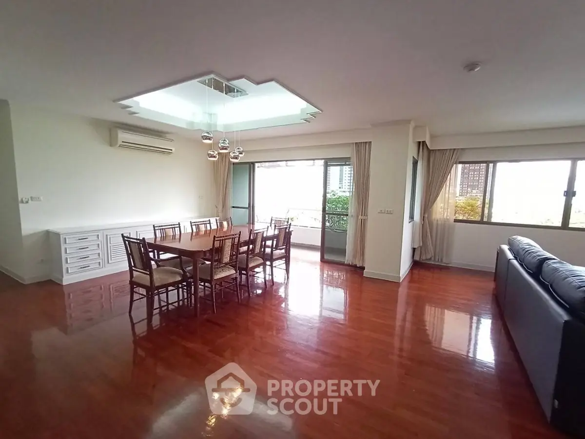 Spacious living room with elegant dining area and large windows offering natural light.