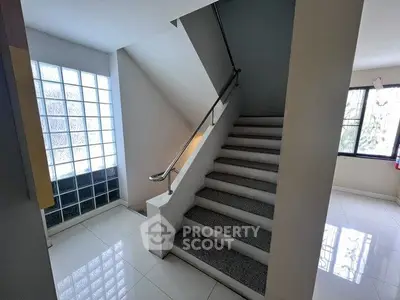 Modern staircase with glass block wall and sleek handrail in bright interior space.