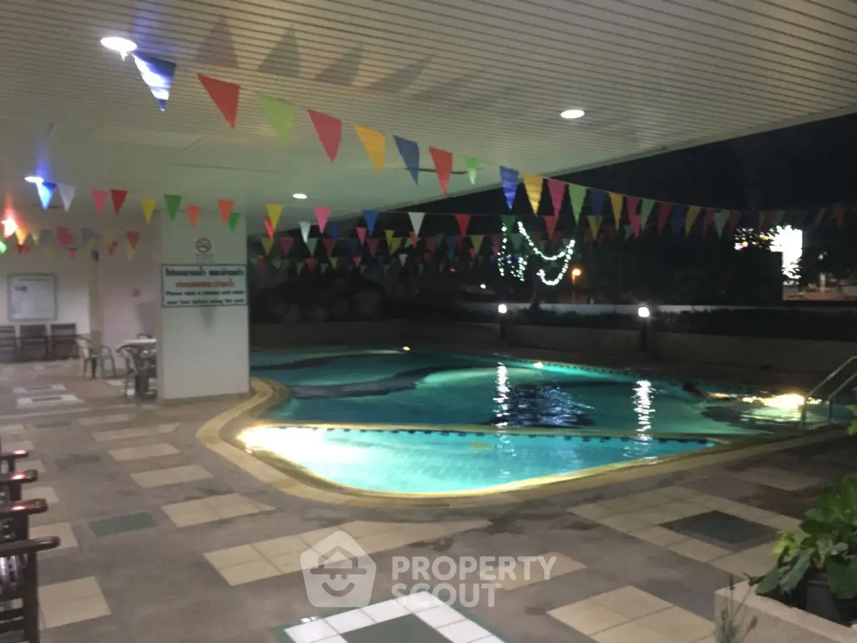 Inviting nighttime pool area with festive lighting and colorful flags, perfect for relaxation and entertainment.