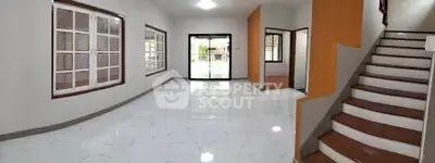 Spacious modern living room with large windows and staircase