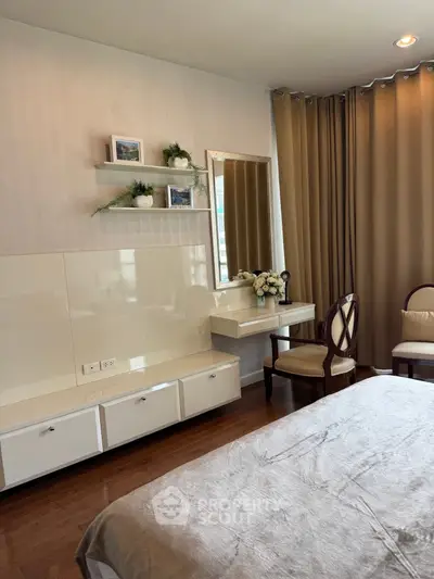 Elegant bedroom with vanity and modern decor, featuring warm lighting and stylish furnishings.