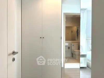 Modern bathroom with sleek design and white cabinetry, featuring a contemporary toilet and shower area.