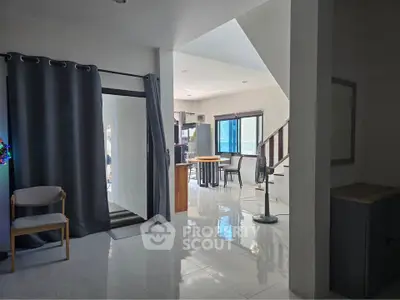 Spacious modern living area with open layout and sleek design, featuring large windows and stylish furniture.