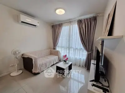 Cozy living room with modern decor, featuring a comfortable sofa, air conditioning, and a flat-screen TV.