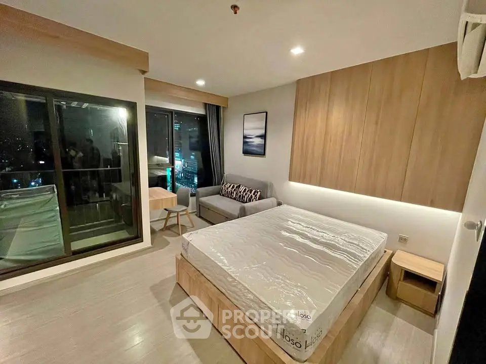 Modern bedroom with large window and city view, featuring a cozy bed and stylish decor.