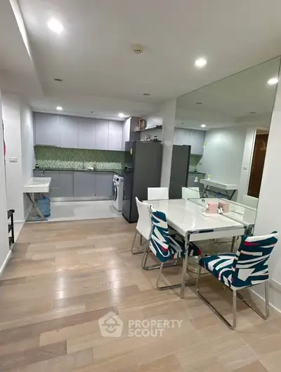 Modern open-layout kitchen and dining area with stylish chairs and wooden flooring.