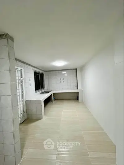 Spacious tiled kitchen with ample counter space and modern lighting, perfect for culinary enthusiasts.