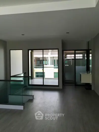 Modern interior with sleek glass railing and large windows offering ample natural light.