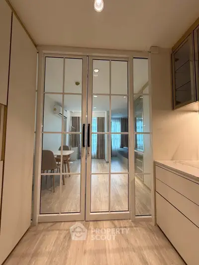 Modern interior with glass doors leading to a stylish living area, featuring elegant flooring and contemporary design.