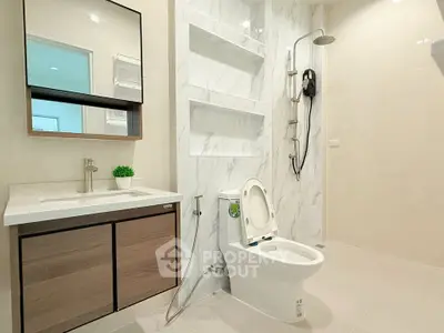 Modern bathroom with sleek fixtures and marble accents, featuring a spacious shower and elegant vanity.