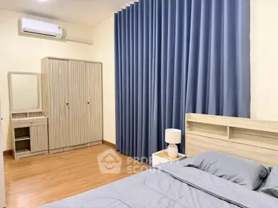 Cozy bedroom with modern furnishings and blue curtains, perfect for relaxation.