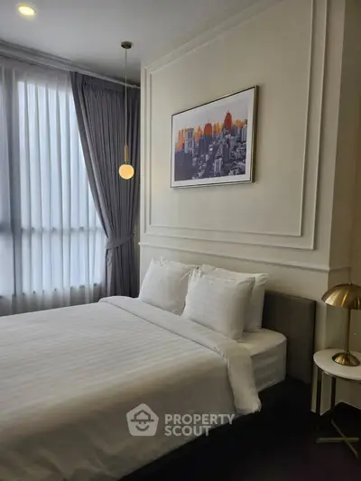 Elegant bedroom with modern decor and large window, featuring stylish lighting and framed artwork.