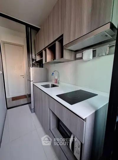 Modern compact kitchen with sleek cabinetry and built-in appliances in a stylish apartment.