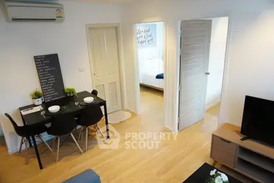 Modern apartment interior with dining area and view into bedroom, featuring stylish decor and wooden flooring.