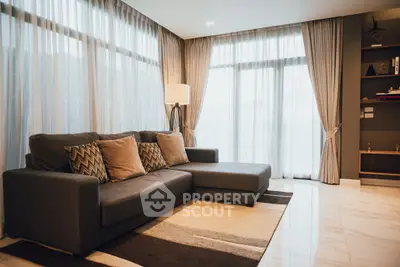 Spacious modern living room with large windows and elegant decor.