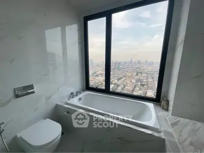 Luxurious bathroom with stunning city view from large window, featuring elegant marble finishes and modern fixtures.