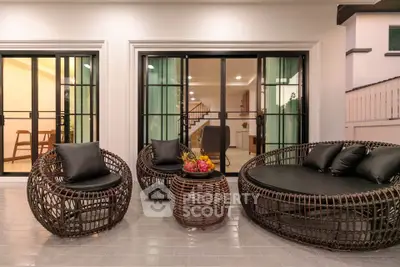 Stylish modern patio with wicker furniture and glass doors leading to elegant interior.
