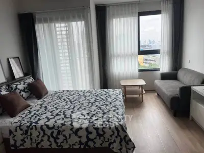 Modern bedroom with city view, featuring stylish decor and natural light.