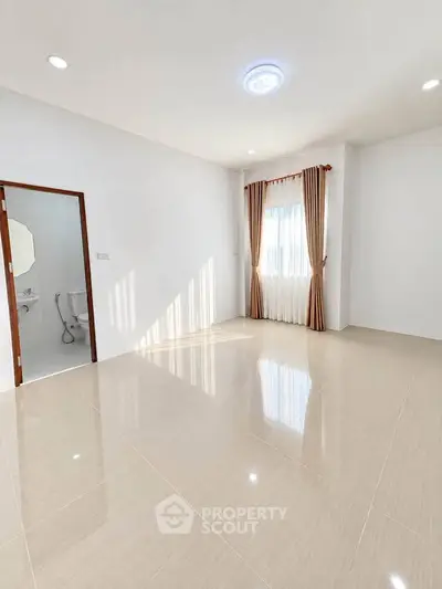 Spacious unfurnished room with large window and elegant curtains, perfect for customization.