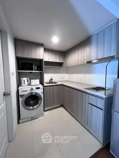 Modern kitchen with sleek cabinetry and built-in appliances, featuring a washing machine and compact design.
