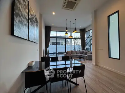 Spacious modern living room with high ceilings and large windows offering natural light and outdoor views.