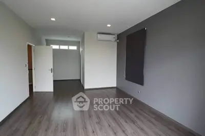 Spacious empty room with modern flooring and air conditioning unit