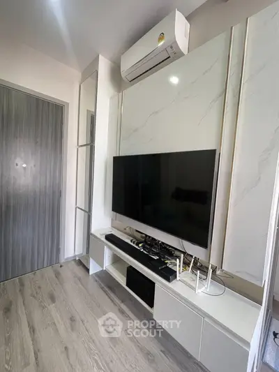 Modern living room with sleek TV setup and air conditioning unit, featuring stylish flooring and contemporary design.