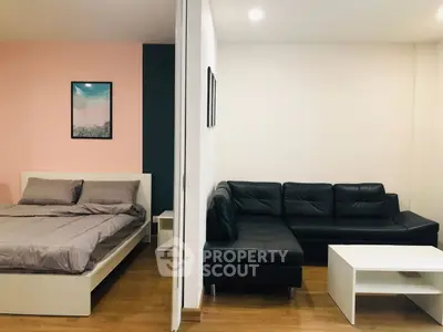 Modern studio apartment with cozy bed and stylish black leather sofa.