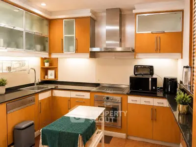 Modern kitchen with wooden cabinets, stainless steel appliances, and sleek black countertops.