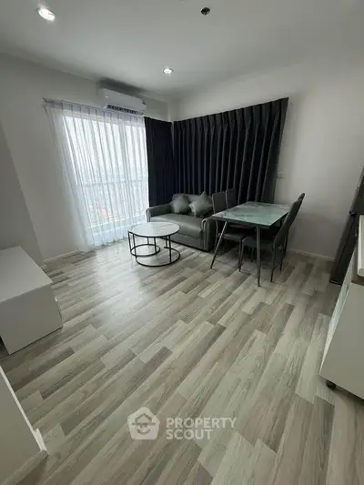 Modern living room with sleek furniture and large window offering natural light.