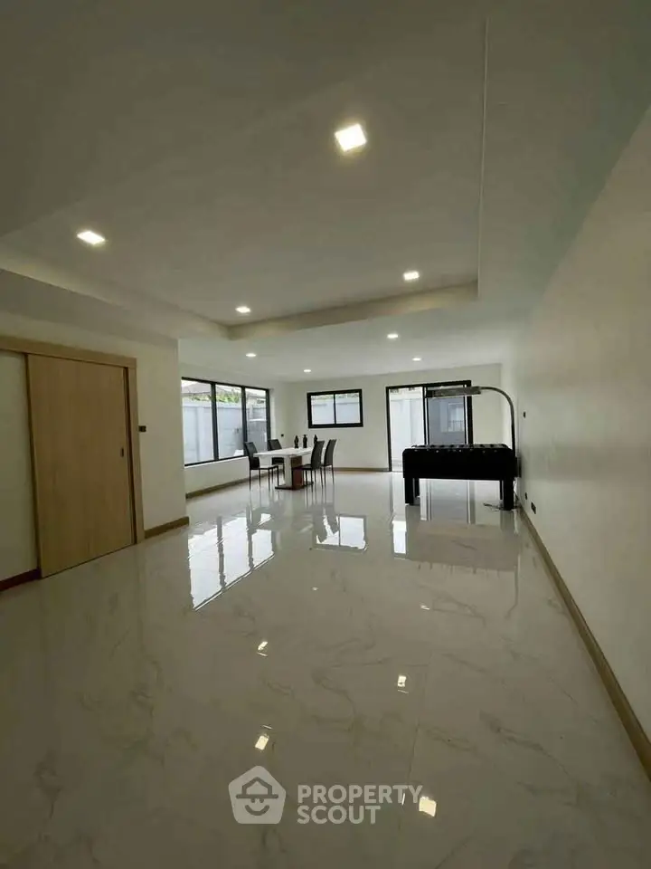 Spacious modern living room with glossy marble floors and ample natural light.