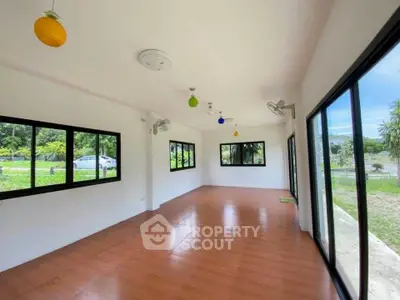 Spacious room with large windows and colorful ceiling lights, offering a serene garden view.