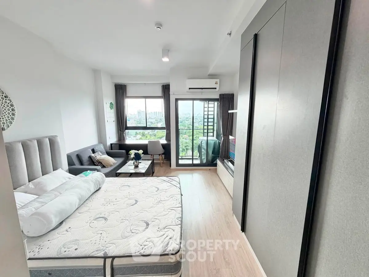 Modern studio apartment with balcony and city view, featuring a cozy living area and stylish decor.