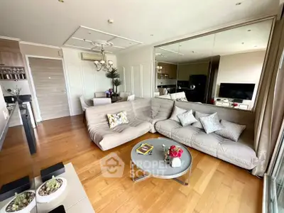 Spacious modern living room with elegant decor and open layout, featuring a cozy sectional sofa and hardwood floors.