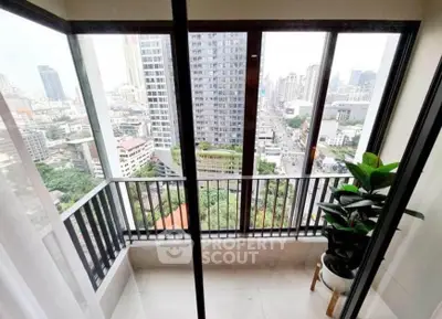 Stunning city view from a modern high-rise balcony with glass doors and lush greenery.