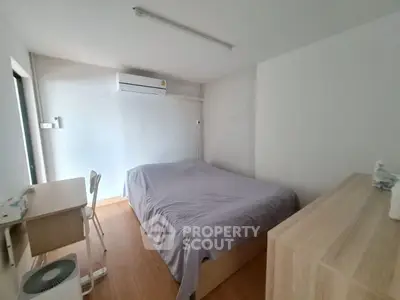 Cozy minimalist bedroom with wooden flooring and modern furniture, perfect for a serene living experience.