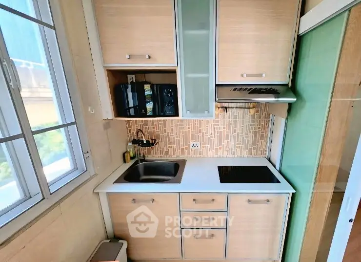 Compact kitchen with modern appliances and sleek cabinetry in a cozy apartment setting.